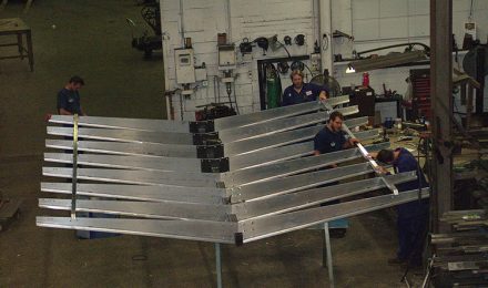 Four men attaching pieces of steel fabricated Starbucks canopy