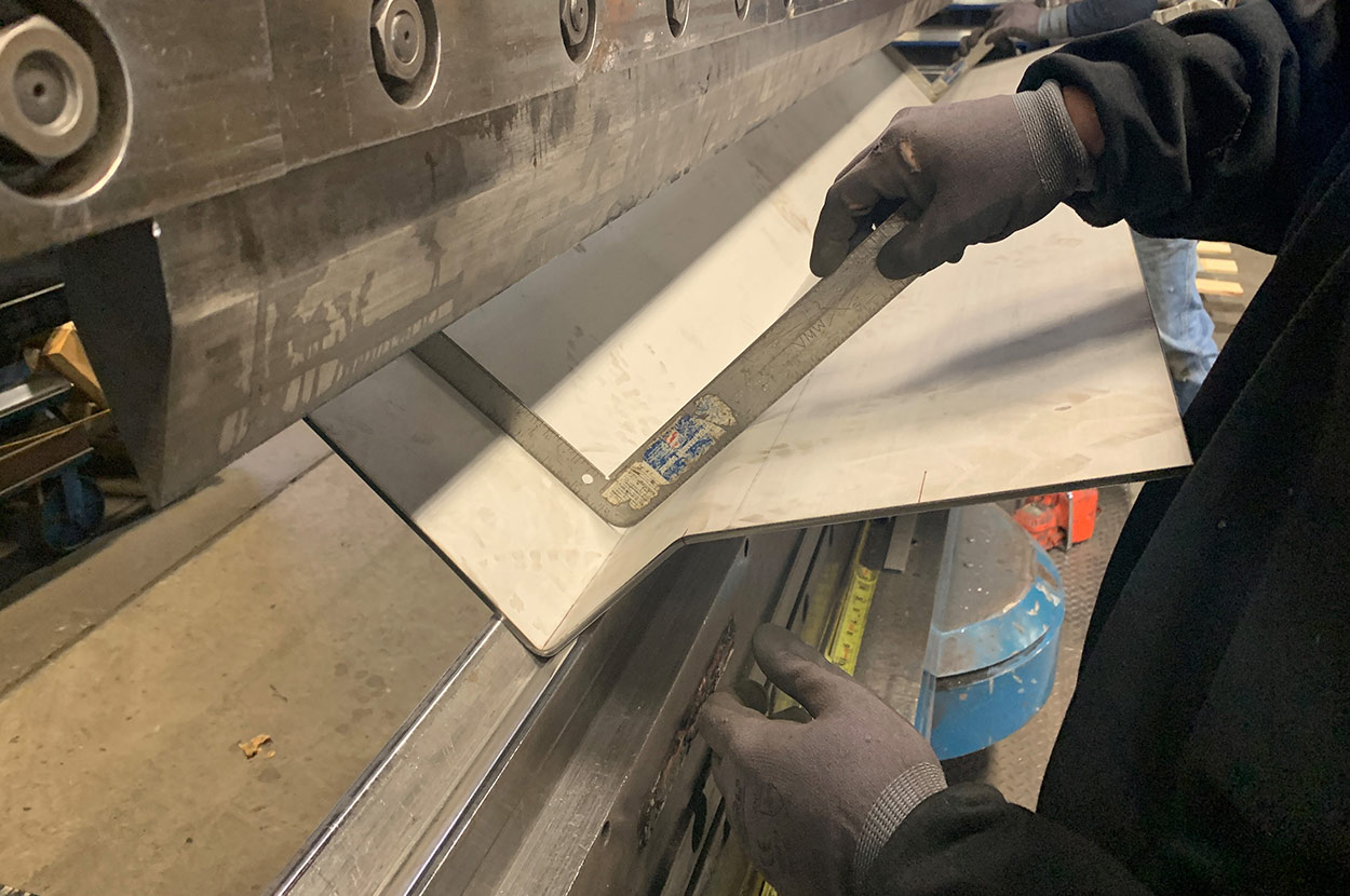 Press brake worker measuring angle of metal fold